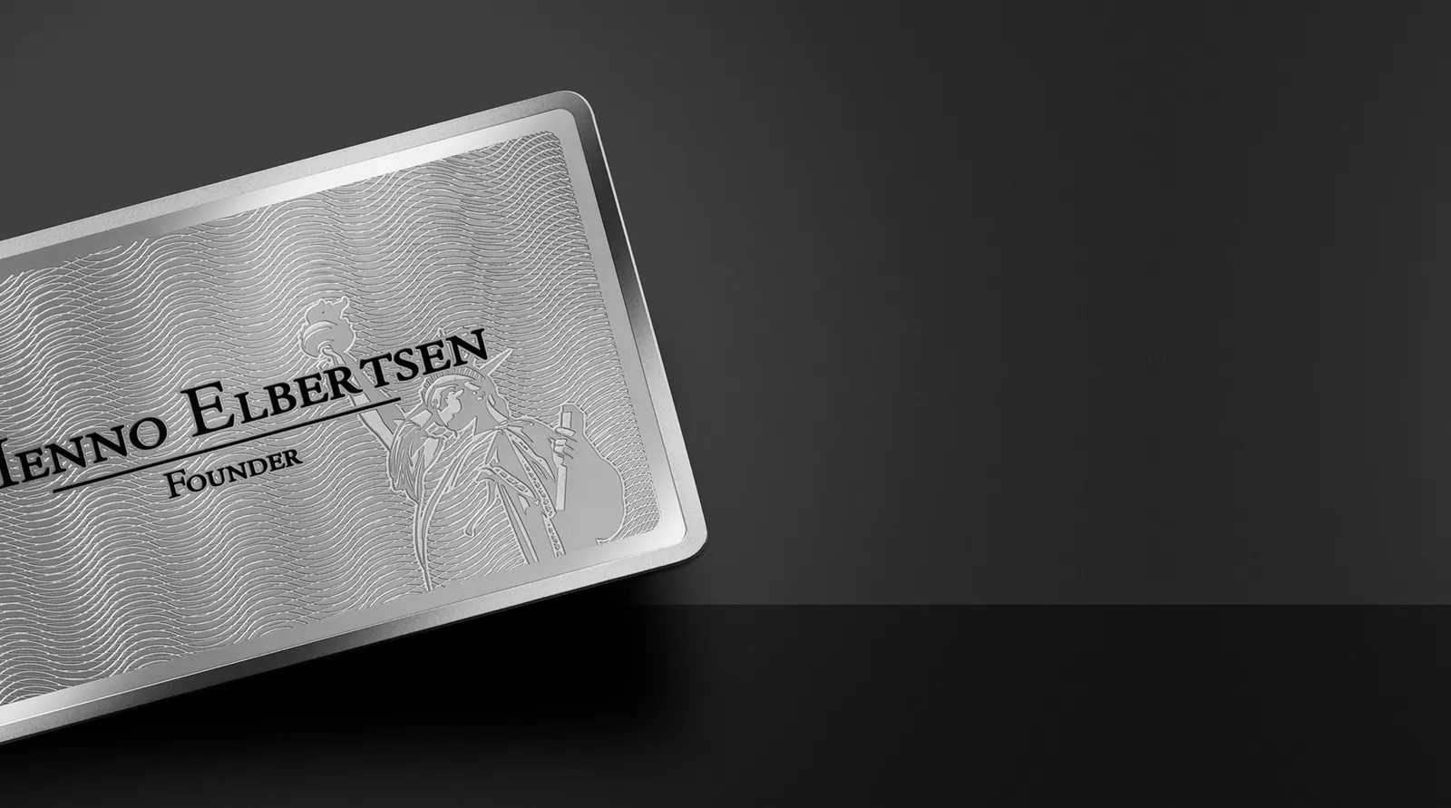 Cardique silver metal business card resting on a dark surface